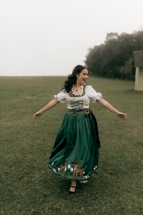 Free Smiling woman dancing outdoors in traditional Bavarian dirndl, embodying joy and cultural heritage. Stock Photo