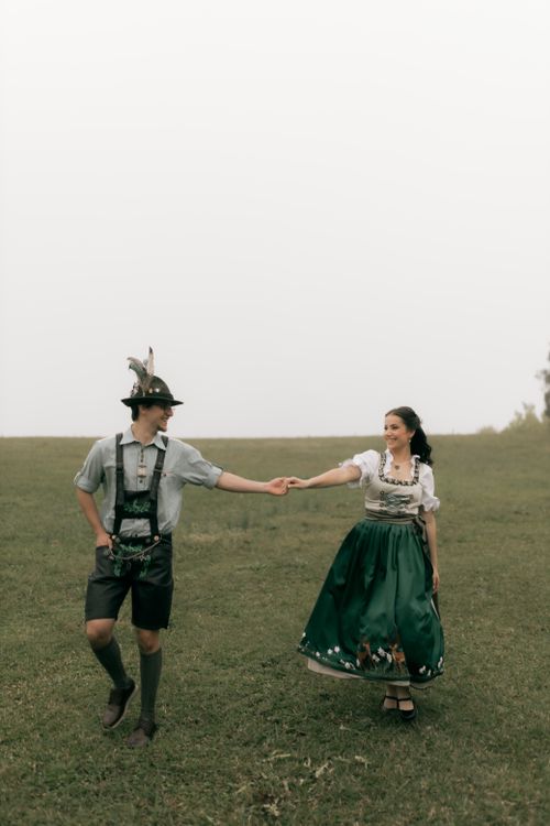 Free A couple in traditional Bavarian attire dances in an open field. Stock Photo