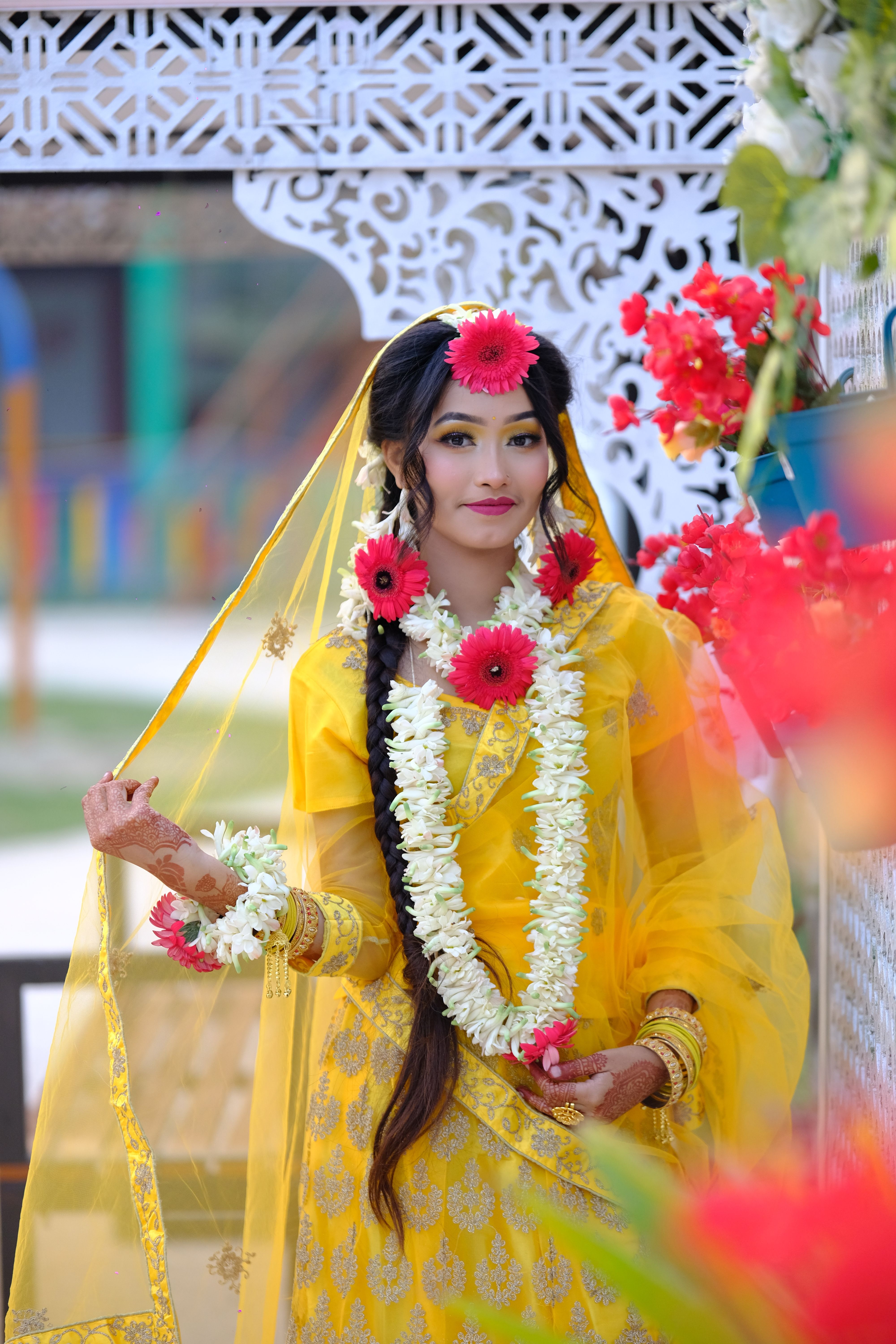 Beautiful bride in yellow saree adorned with flowers, showcasing traditional wedding attire.