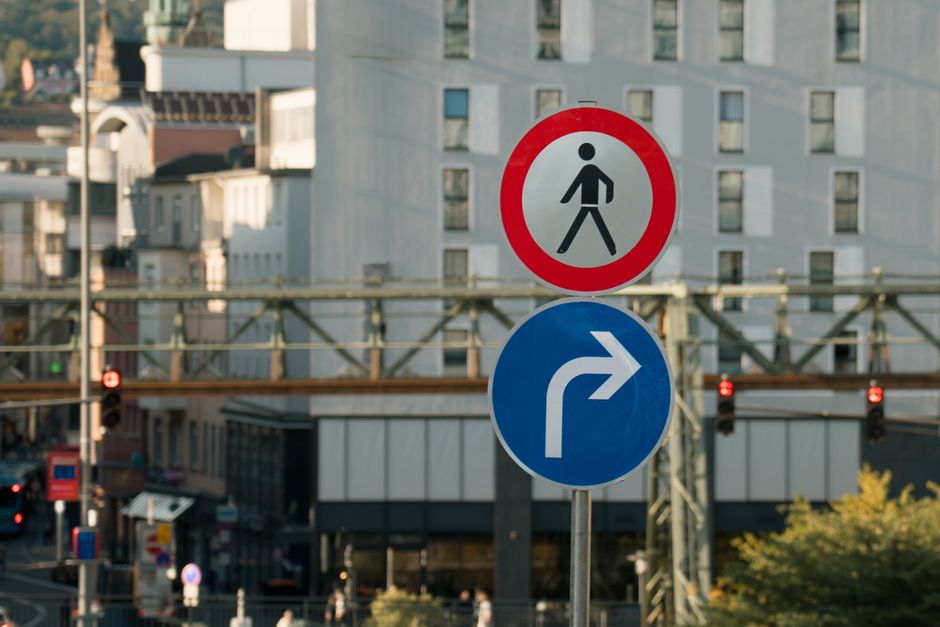 Traffic signs indicating pedestrian prohibition and right turn in a bustling European city.