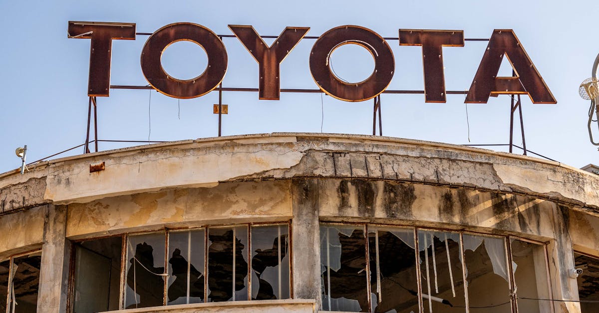 Photo by halil yiğit Rusty Toyota sign atop a derelict building with broken windows in Cyprus.