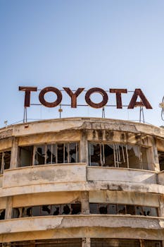 Rusty Toyota sign atop a derelict building with broken windows in Cyprus.