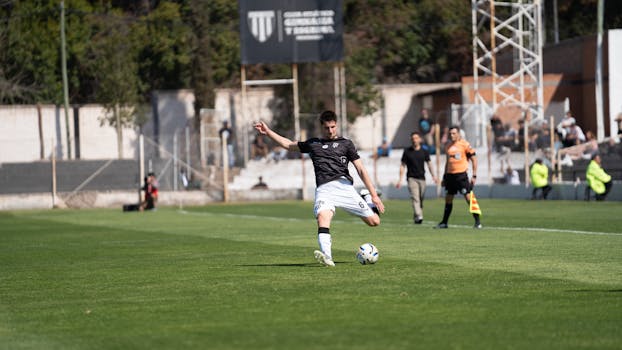 Football player kicking ball during match on sunny day.
