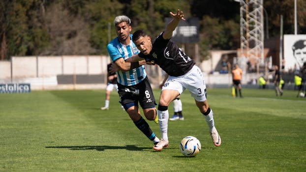 Two players in action during a competitive football match in daylight.