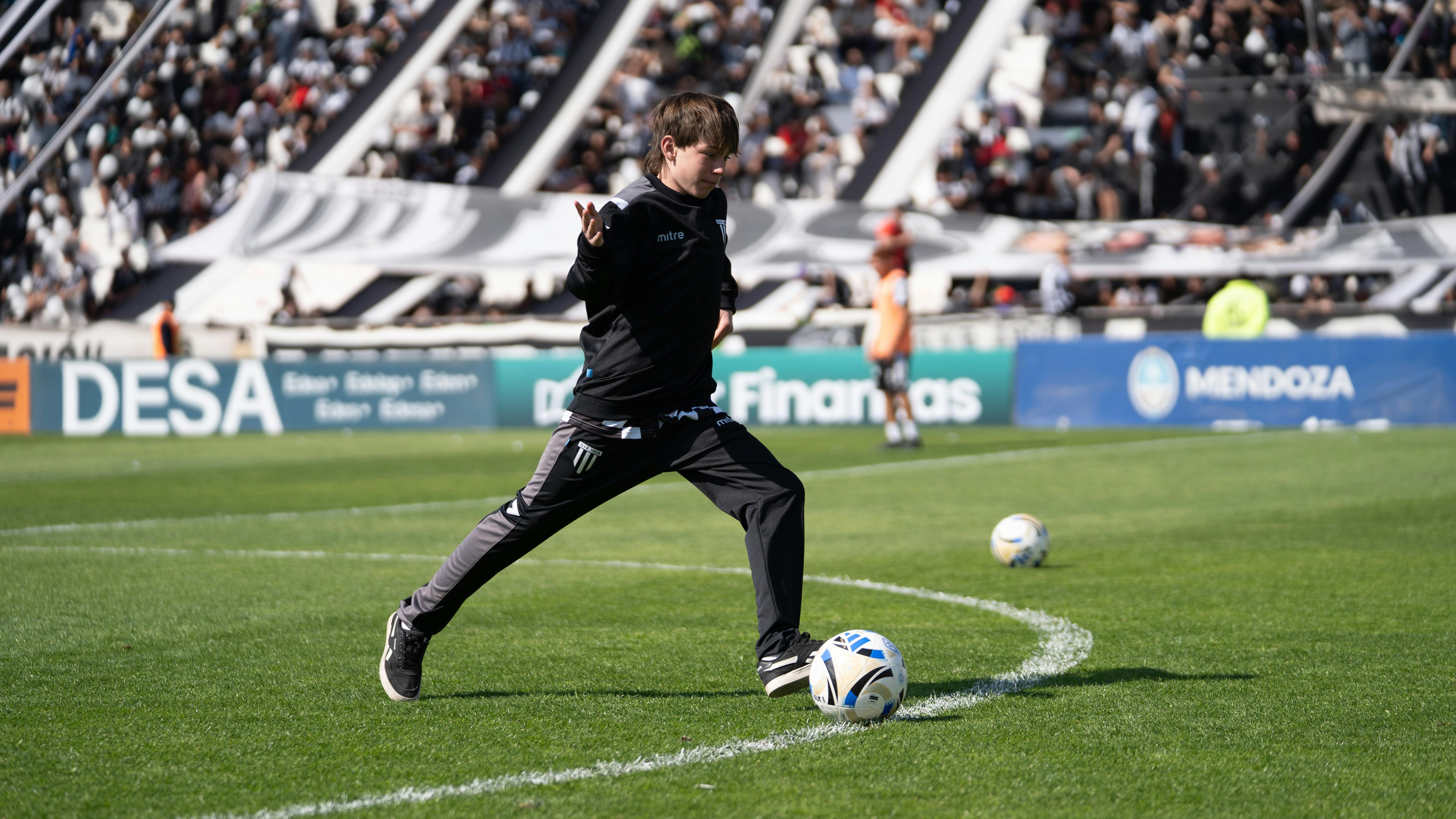 A young soccer player skillfully kicking a football on a vibrant green field during a lively outdoor match.