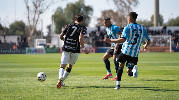 Soccer players in action on the field during a sunny day match.