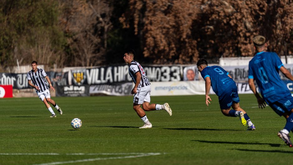 Dynamic football match on a sunny day with players in action on the field.