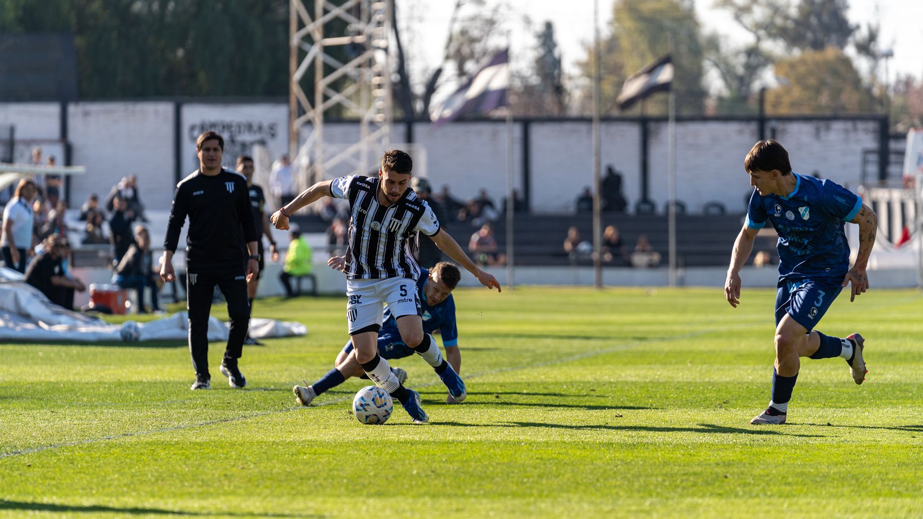 Players engaged in a competitive football game on a sunny day outdoors.