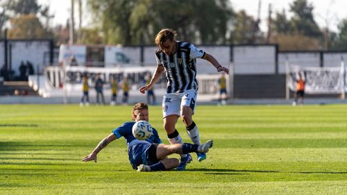 Free Exciting football tackle scene during a match on a sunny day in a professional stadium. Stock Photo