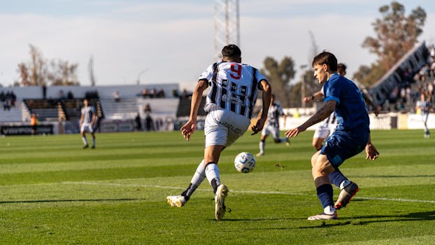 Players in action on the soccer field during an outdoor match under the bright sun.