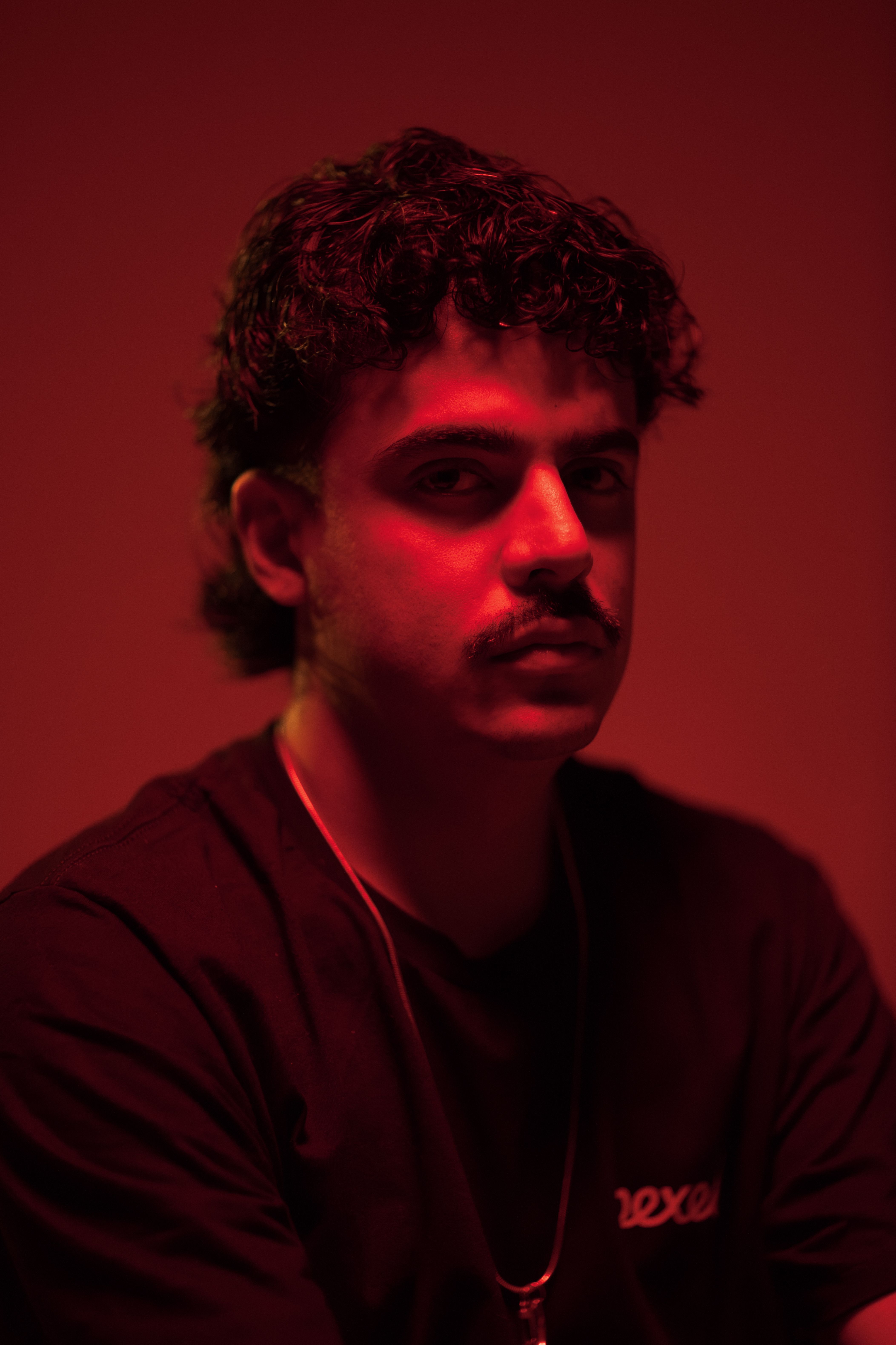 Artistic portrait of a man under red lighting creating a moody atmosphere.
