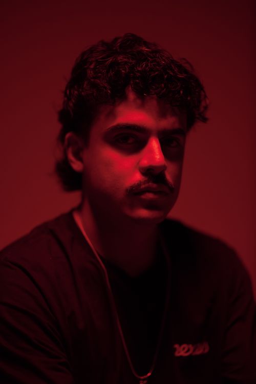 Free Artistic portrait of a man under dramatic red lighting creating a moody atmosphere. Stock Photo