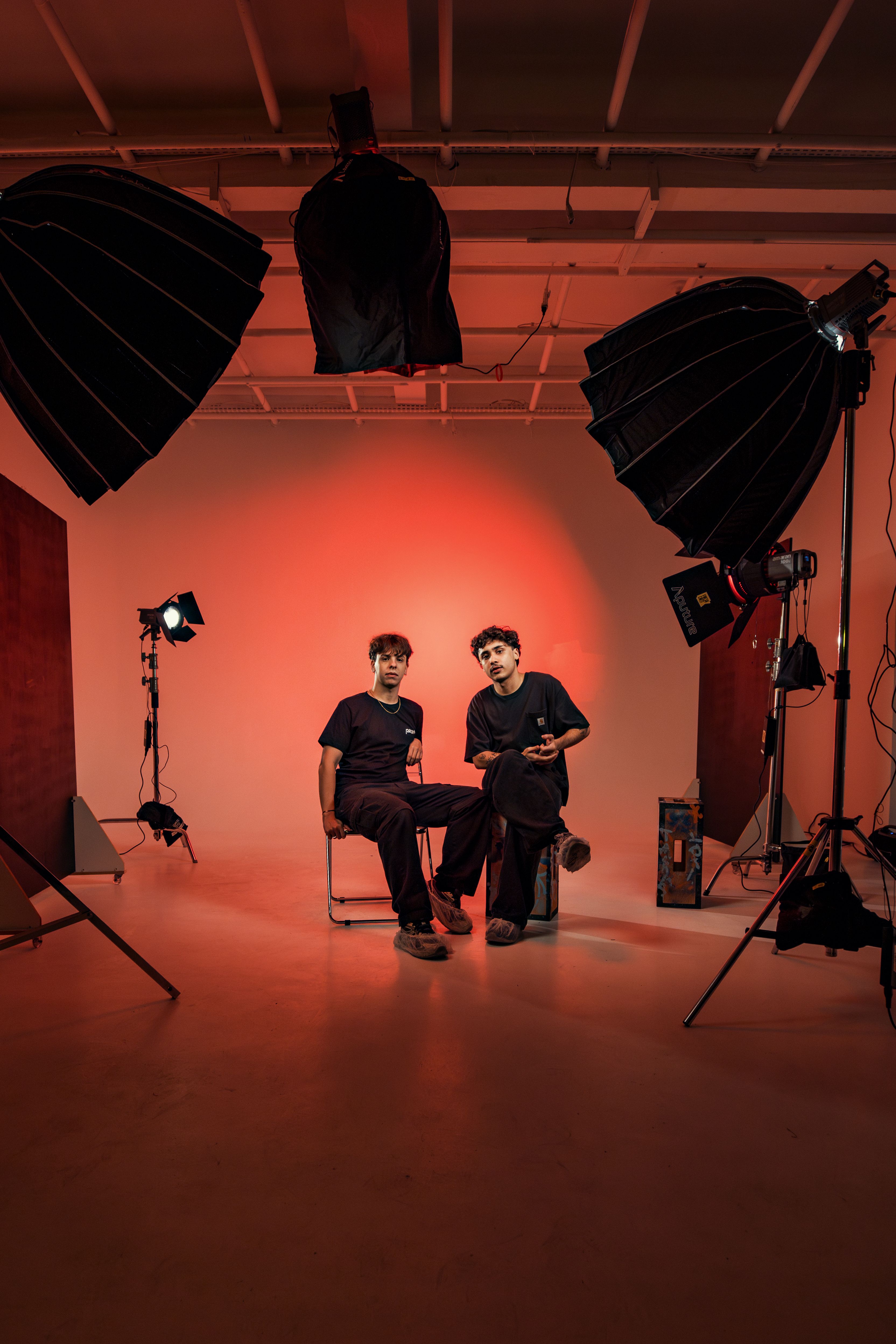 Studio portrait of two adults in artistic lighting setup indoors.