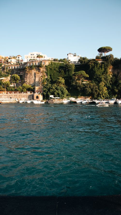Free Picturesque Sorrento coastline with cliffs, villas, and clear water under a bright sky. Stock Photo