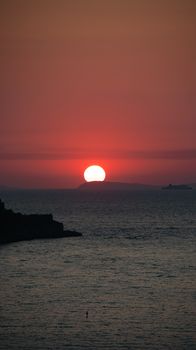 Serene sunset over sea in Sorrento, Italy with vivid red hues and calm waters.
