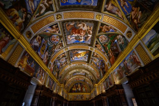 Ornate ceiling paintings in a historic library in Madrid, showcasing Renaissance art.