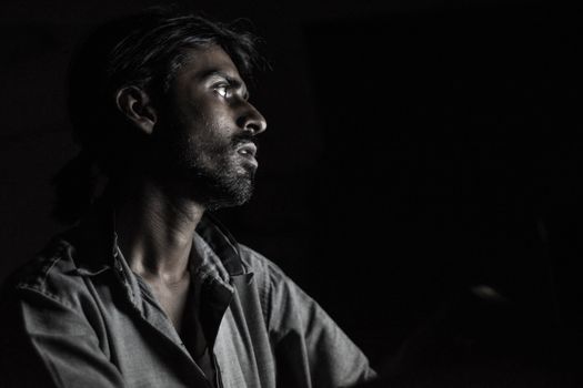 A dramatic side profile portrait of a man captured in moody low light, highlighting expression and emotion.