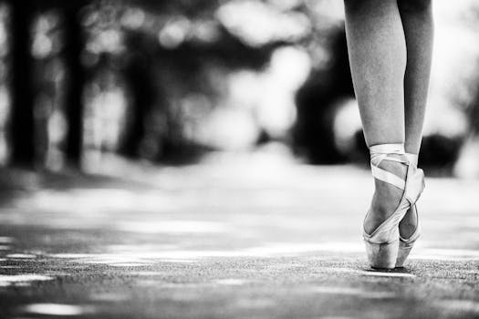 Ballet dancer elegantly standing en pointe outdoors, captured in black and white.