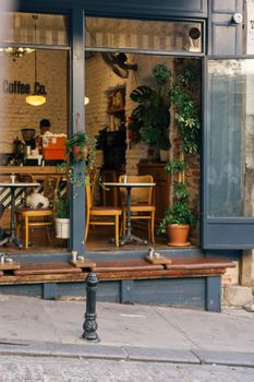 Charming café in İstanbul with potted plants and wooden furniture offering a warm atmosphere indoors.
