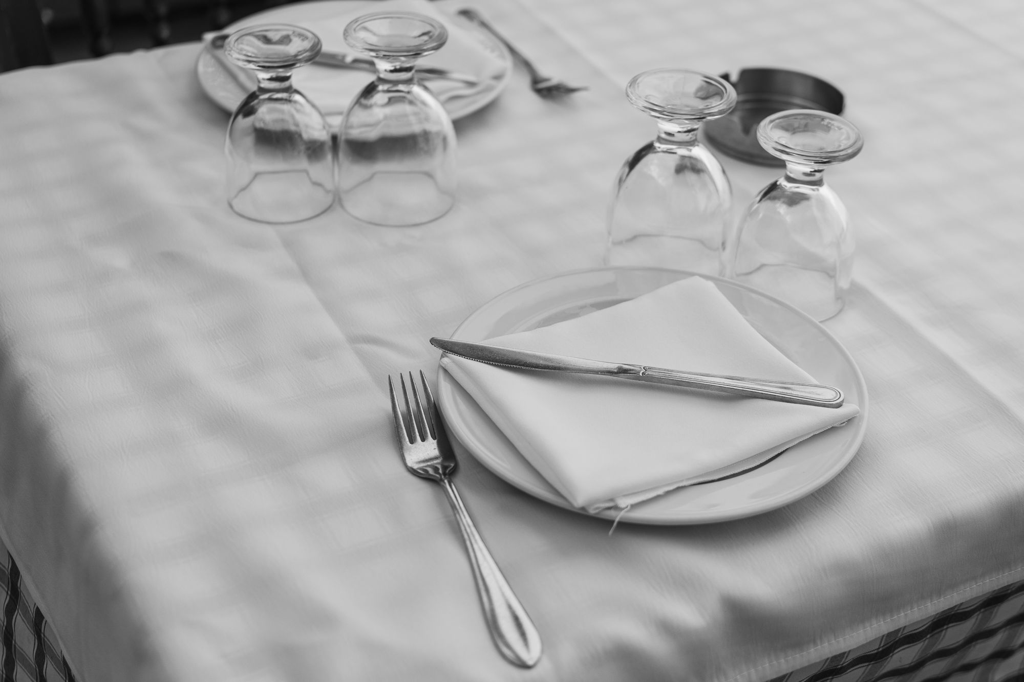 A white linen place setting with a folded napkin and glassware