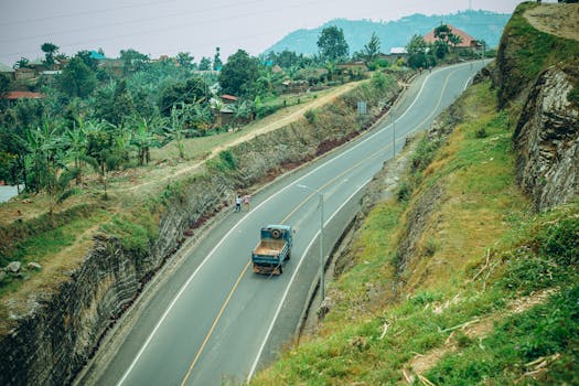 Aerial view of a rural road with a truck passing, surrounded by lush greenery.