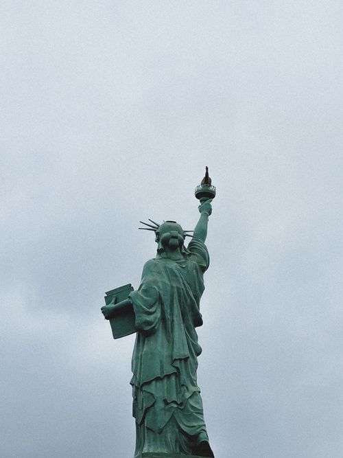 Free The iconic Statue of Liberty with a bird perched on its torch, showcasing freedom and resilience. Stock Photo