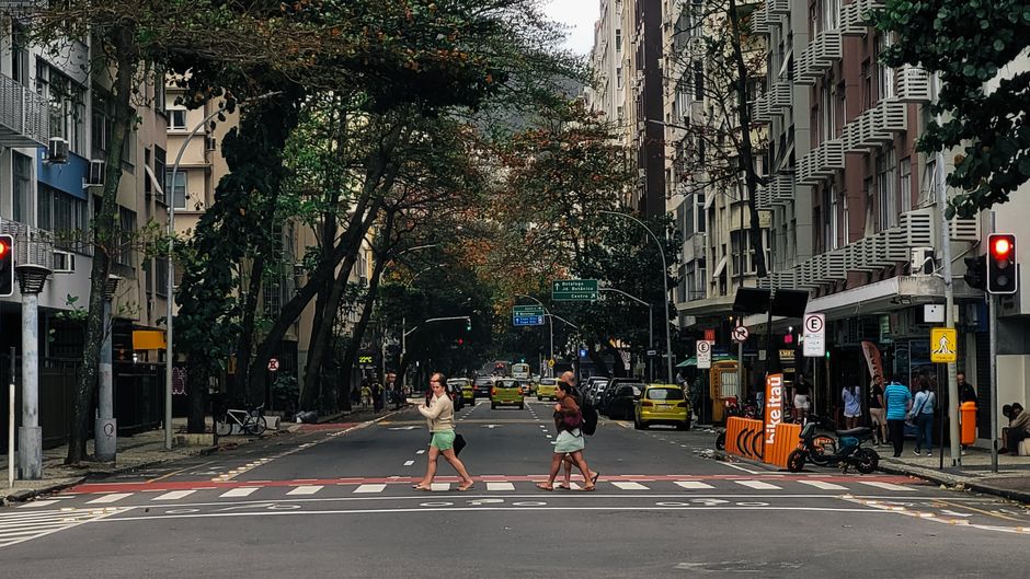 People crossing a street in Copacabana, Rio de Janeiro, surrounded by urban architecture.