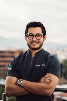 Confident man with glasses smiling outdoors with city background.