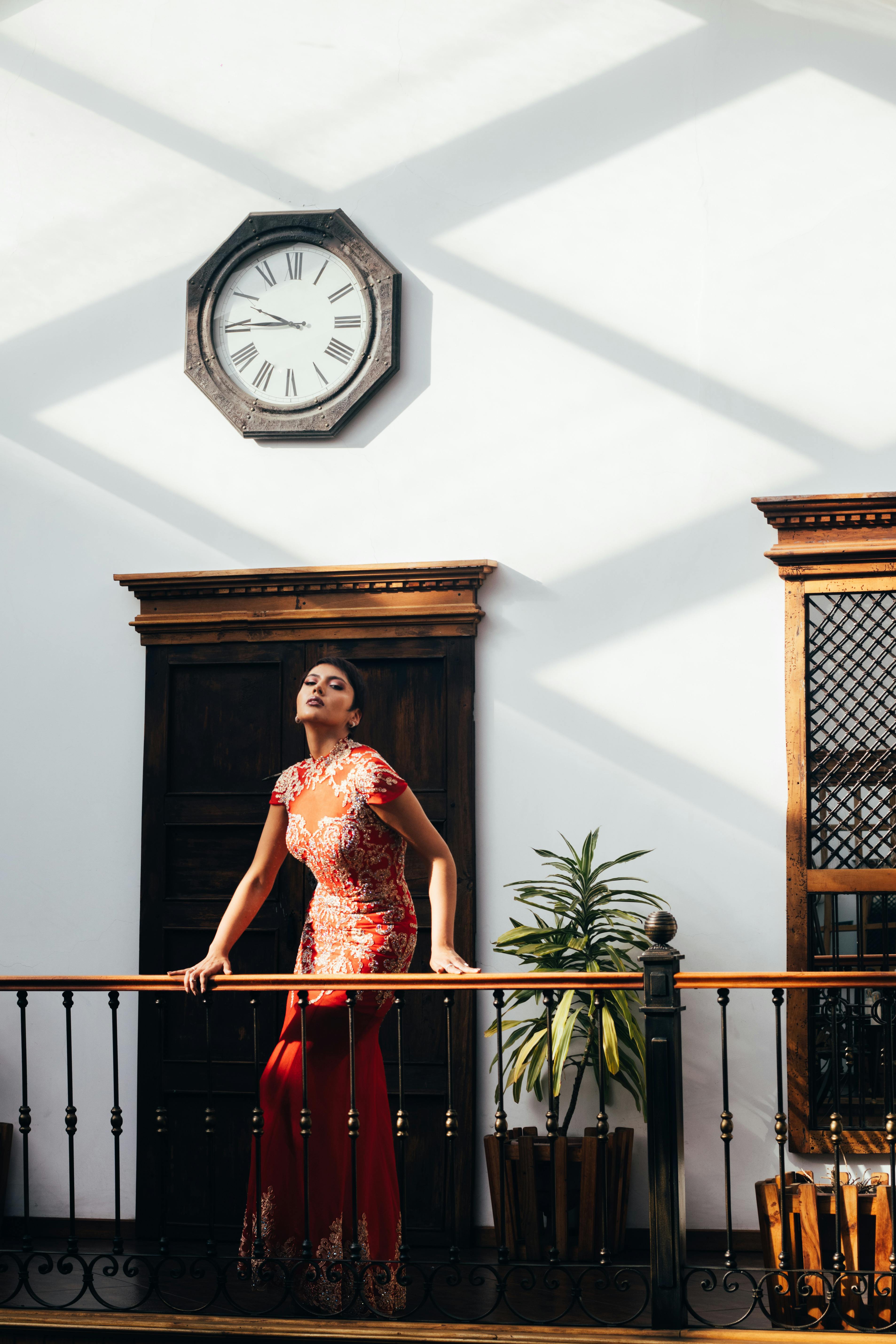 A stylish woman poses in a vibrant dress indoors in Cuenca, Ecuador.