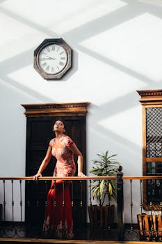 A stylish woman poses in a vibrant dress indoors in Cuenca, Ecuador.
