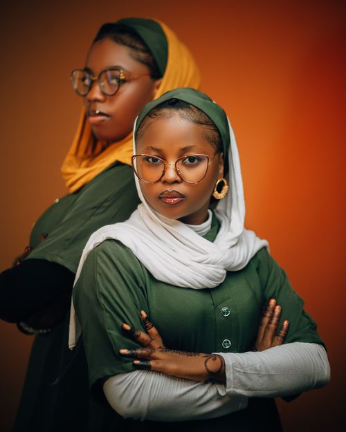 Free Stylish portrait of two Nigerian women in hijabs with confident poses against a warm background. Stock Photo