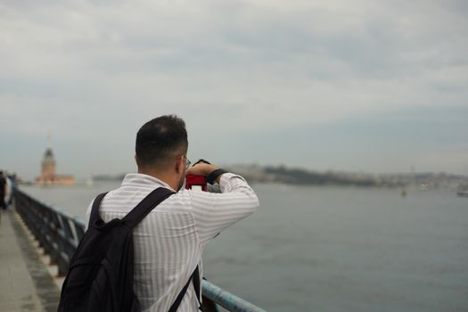 A person photographing the scenic waterfront with Maiden's Tower in İstanbul, Türkiye.