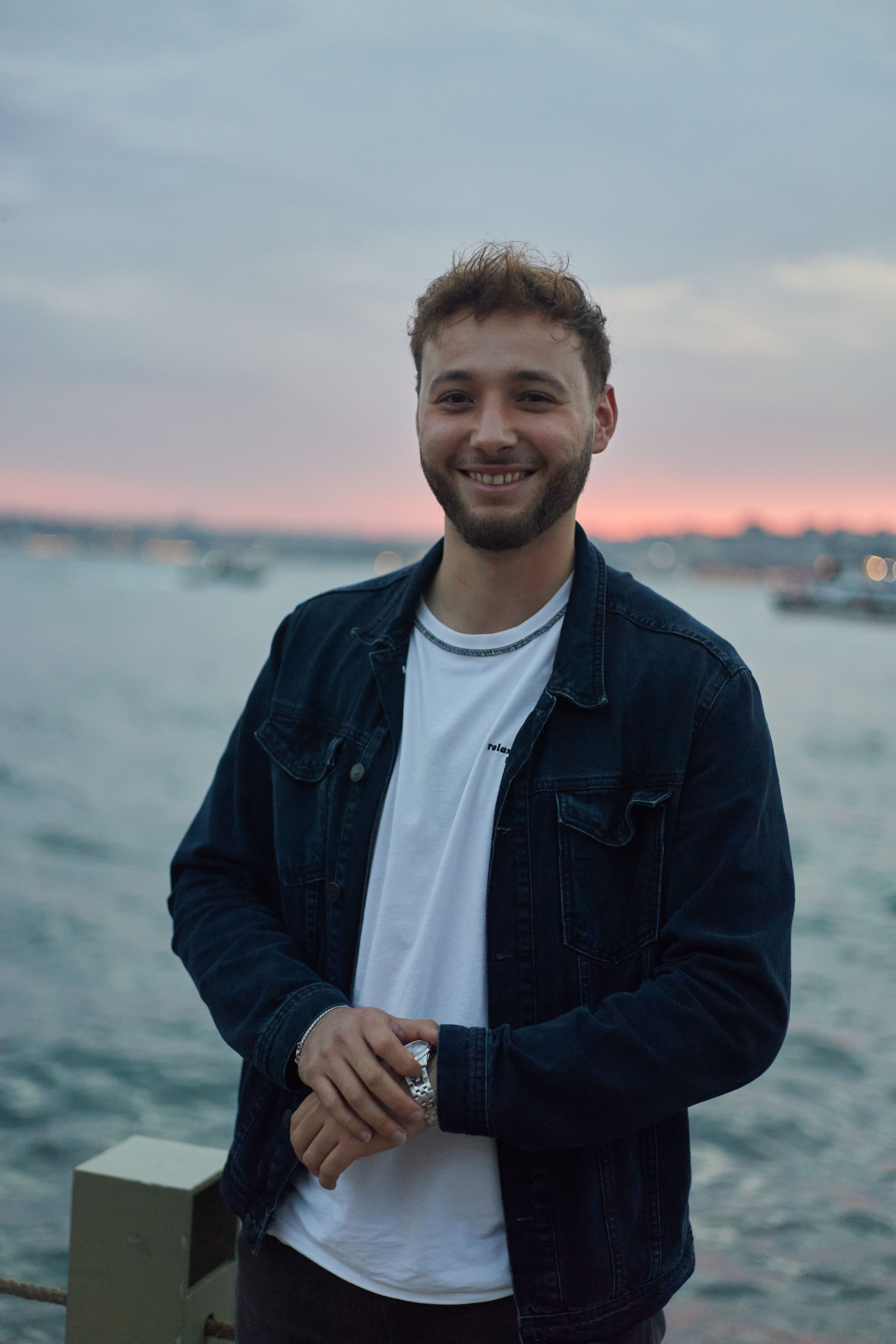Young man smiling by the sea at sunset in Istanbul, Türkiye.