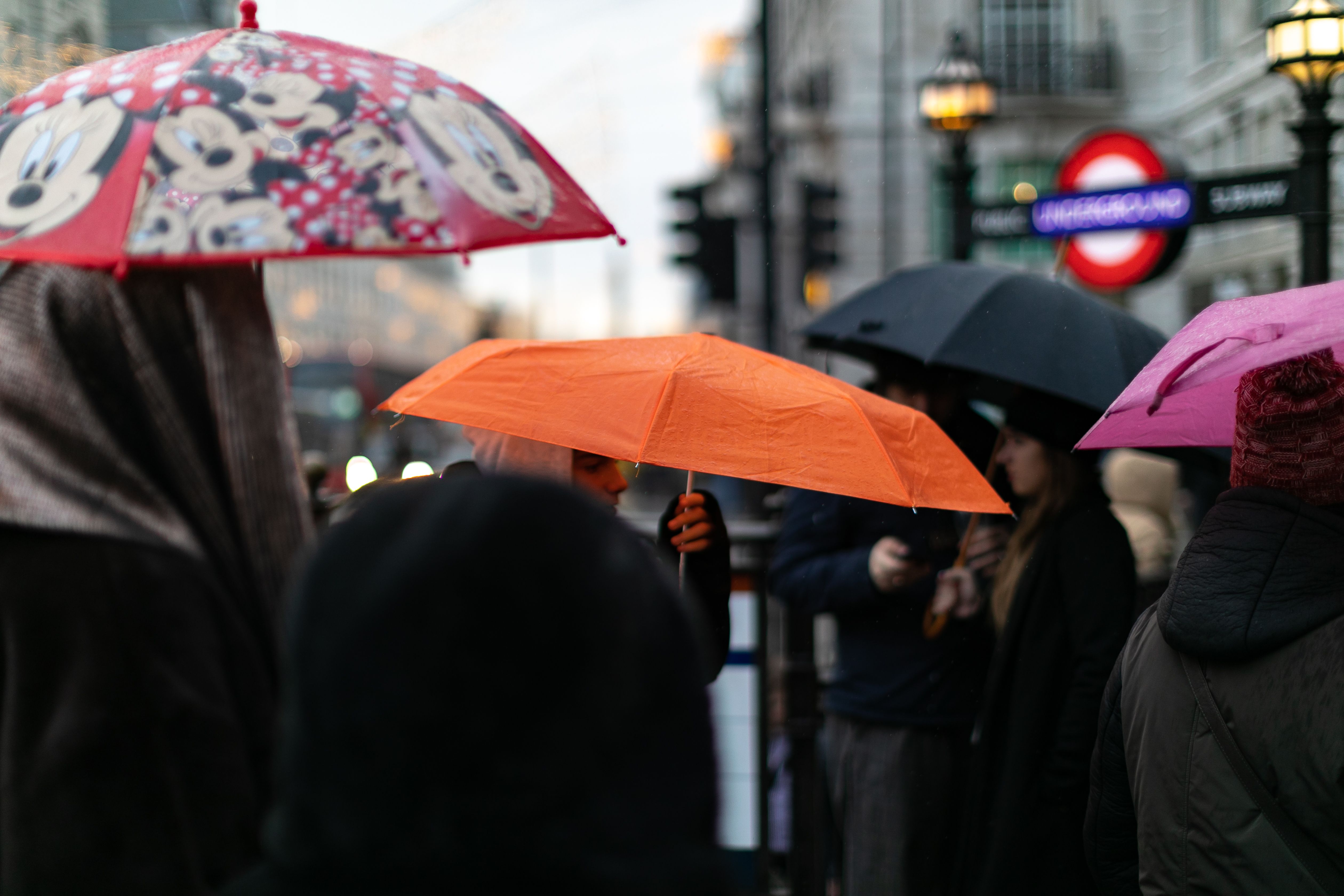 Vibrant umbrellas shelter people from rain on a busy London street.