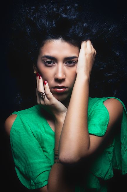 Portrait of a woman in a green dress with curly hair, expressive pose captured in Rio de Janeiro.