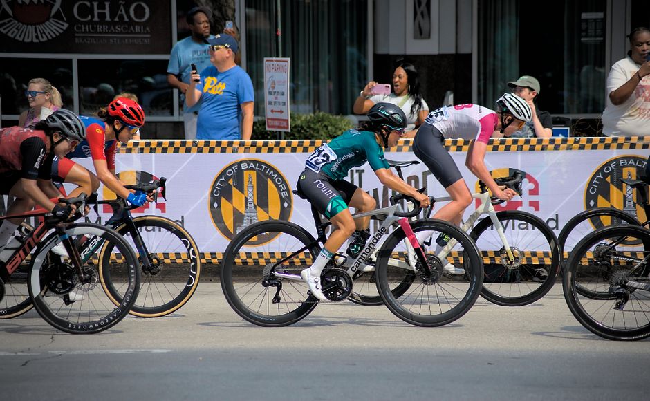 Cyclists racing in Baltimore, Maryland event. Energetic and competitive scene with city backdrop.