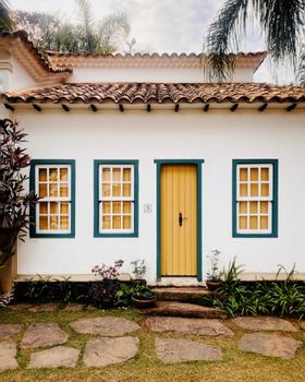 Beautiful colonial house with a vibrant yellow door and lush garden area.