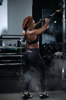 Focused woman exercising with cables at the gym, showcasing strength and determination.