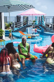 Group of friends enjoying a sunny day by the pool with inflatables and umbrellas.