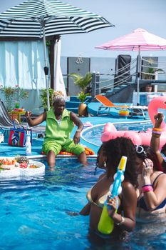 A lively pool party with diverse people enjoying food and fun on a sunny summer day.
