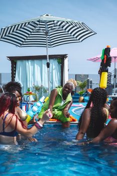 A vibrant pool party with friends enjoying summer fun with water guns and laughter.