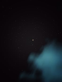 Aesthetic capture of the night sky with a cloudy view of the moon surrounded by stars.