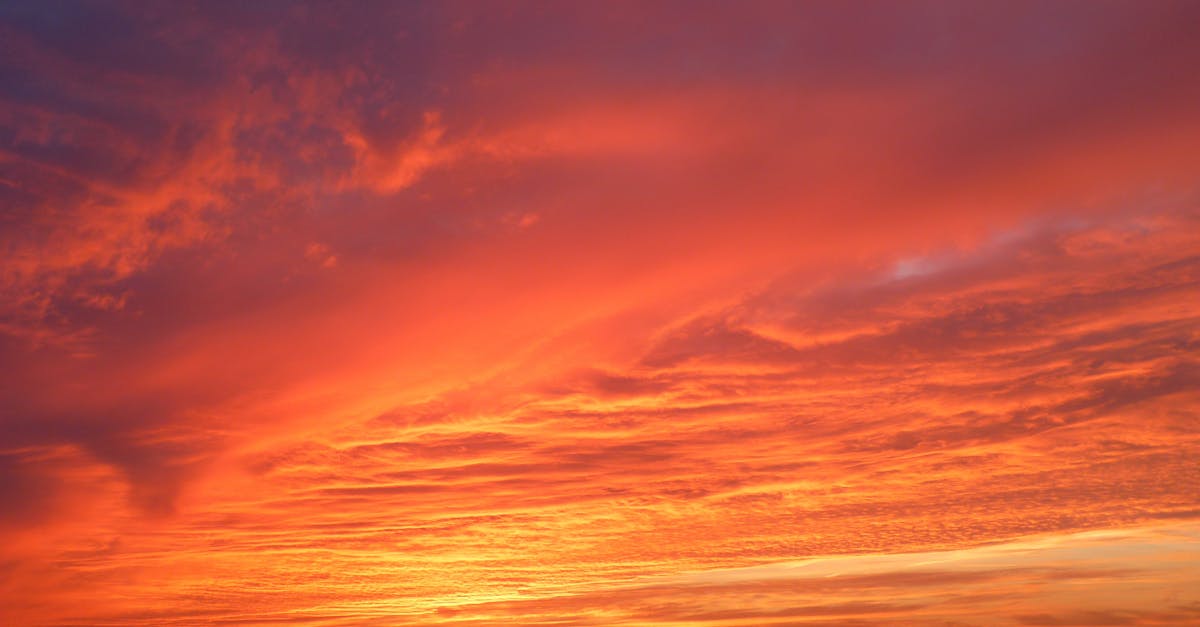 Stunning red sunset with vivid clouds reflecting over tranquil beach waters, capturing nature's beauty.