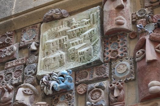Detailed artistic wall featuring a variety of colorful and expressive carvings and sculptures.