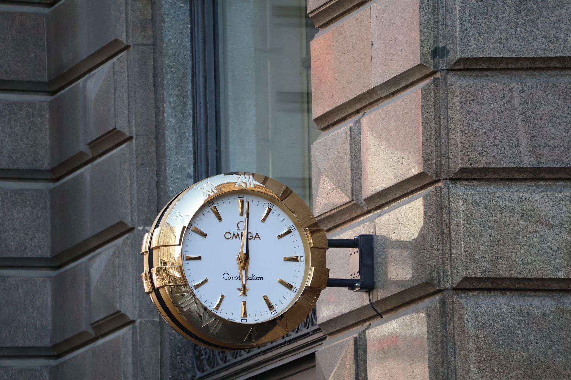 Elegant Omega wall clock adorns a classic urban building facade.
