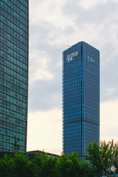 Impressive skyscraper with blue facade under a cloudy sky, reflecting urban architecture.