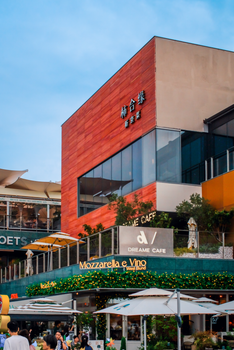 Lively urban scene with cafes, shops, and outdoor seating under a clear sky.
