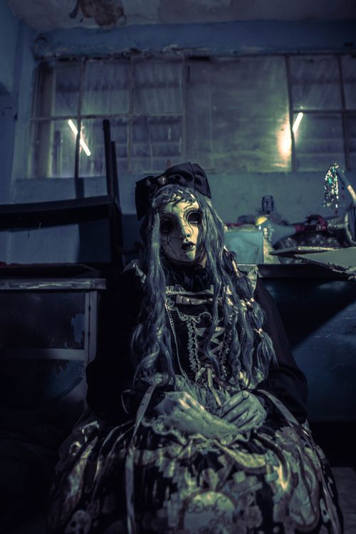 Free Creepy doll in a dimly lit room evokes a sense of horror and mystery. Stock Photo