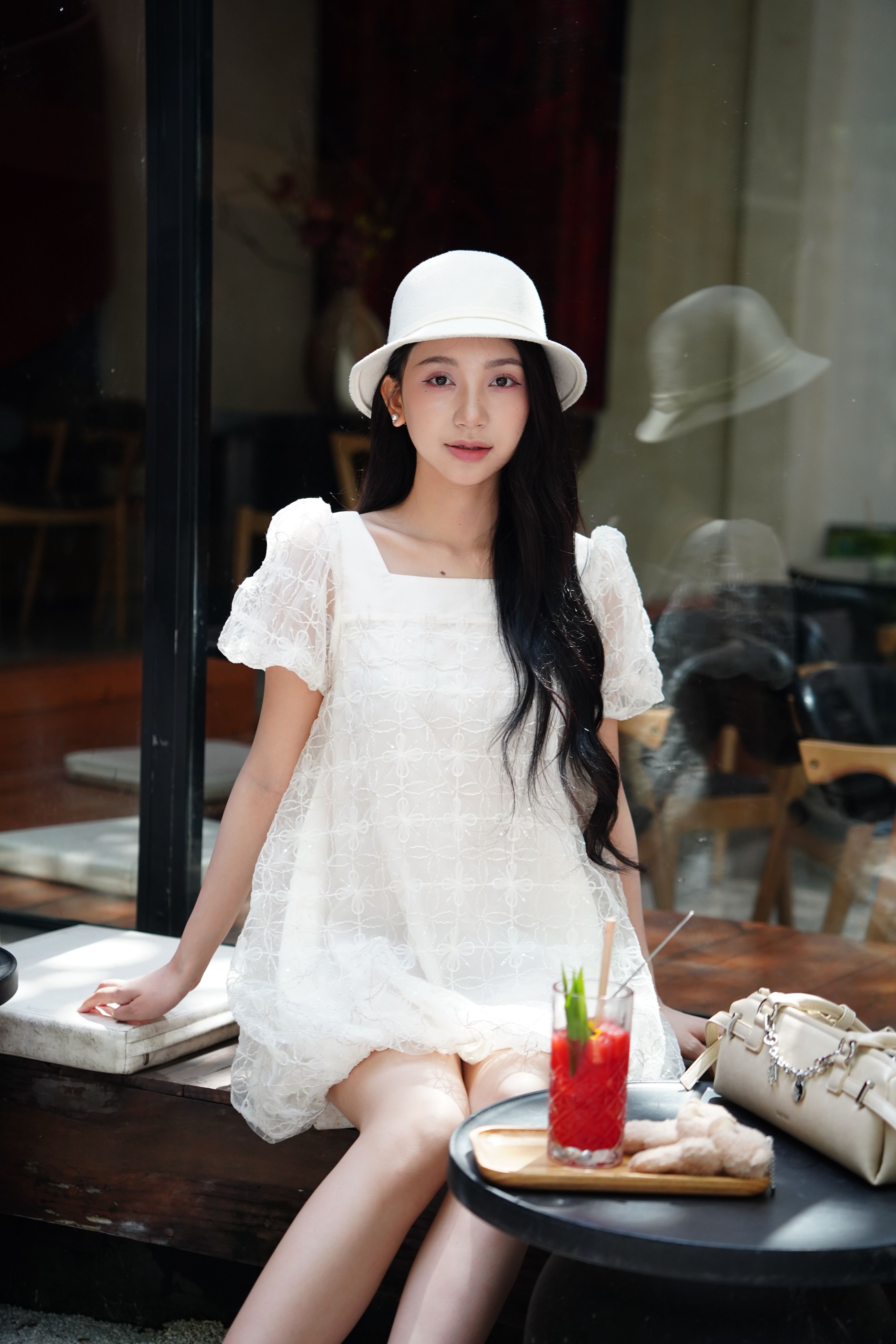 Elegant Woman in White Dress Enjoys Iced Drink at Cafe · Free Stock Photo