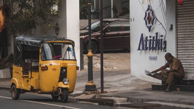 A vibrant yellow auto rickshaw parked on a street, capturing daily life in Puducherry, India.